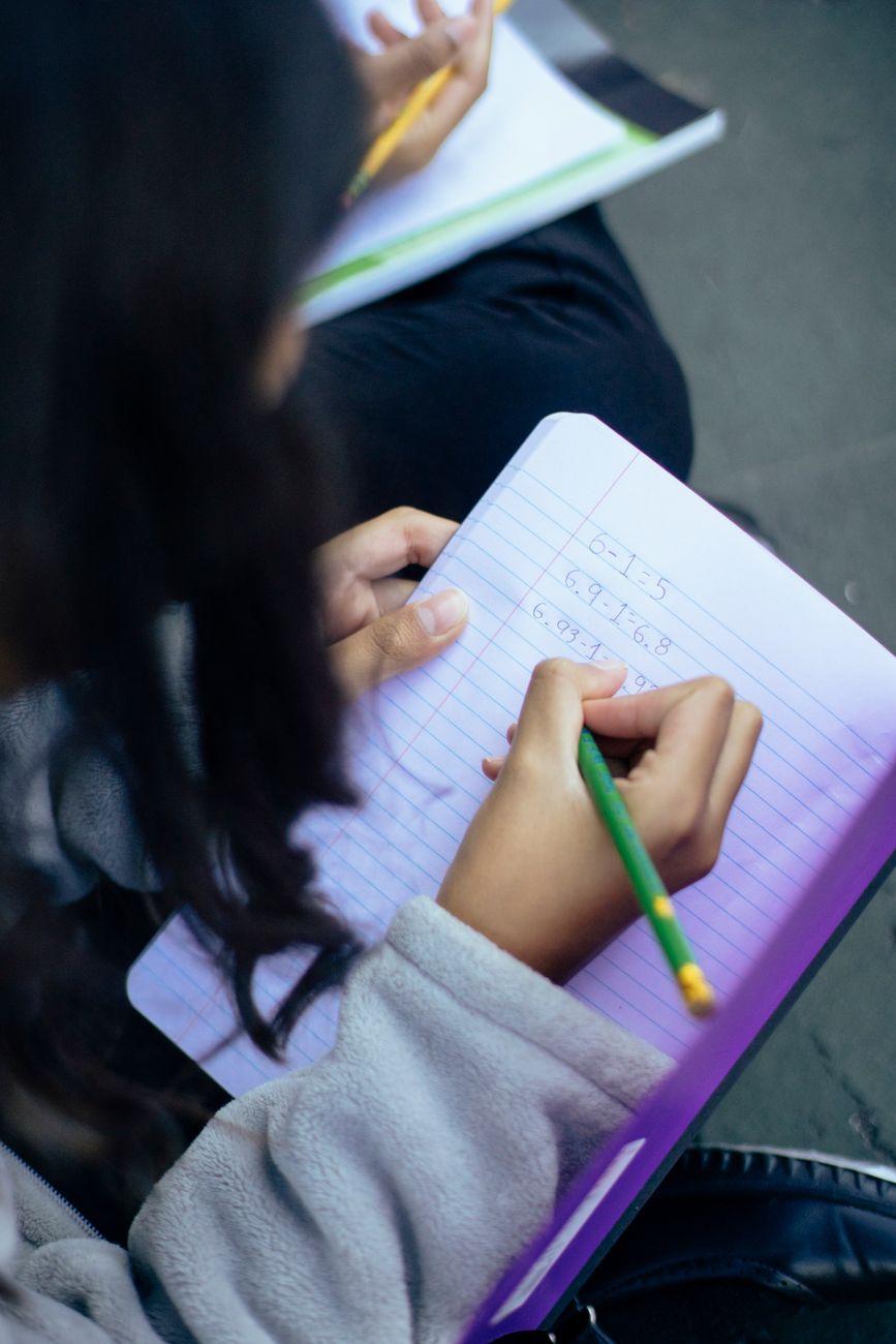 small girl writing numbers in notebook